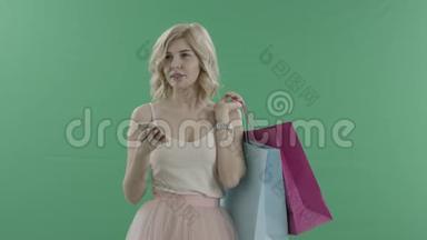 迷人的女人在购物后等人，然后在智能手机上用<strong>绿色</strong>屏幕<strong>上网</strong>